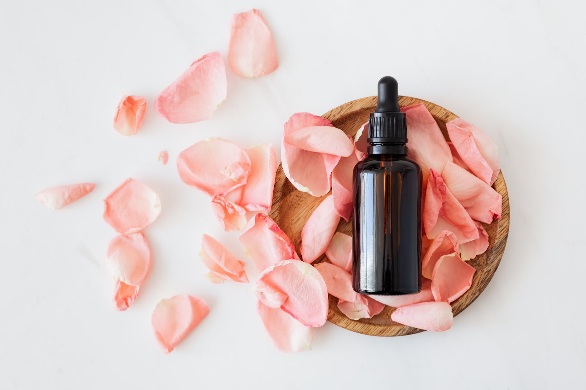 Pink rose petals with a dropper bottle on wood. What is Clean skincare and why you should make the switch. Benefits of clean skincare, brands to try. 