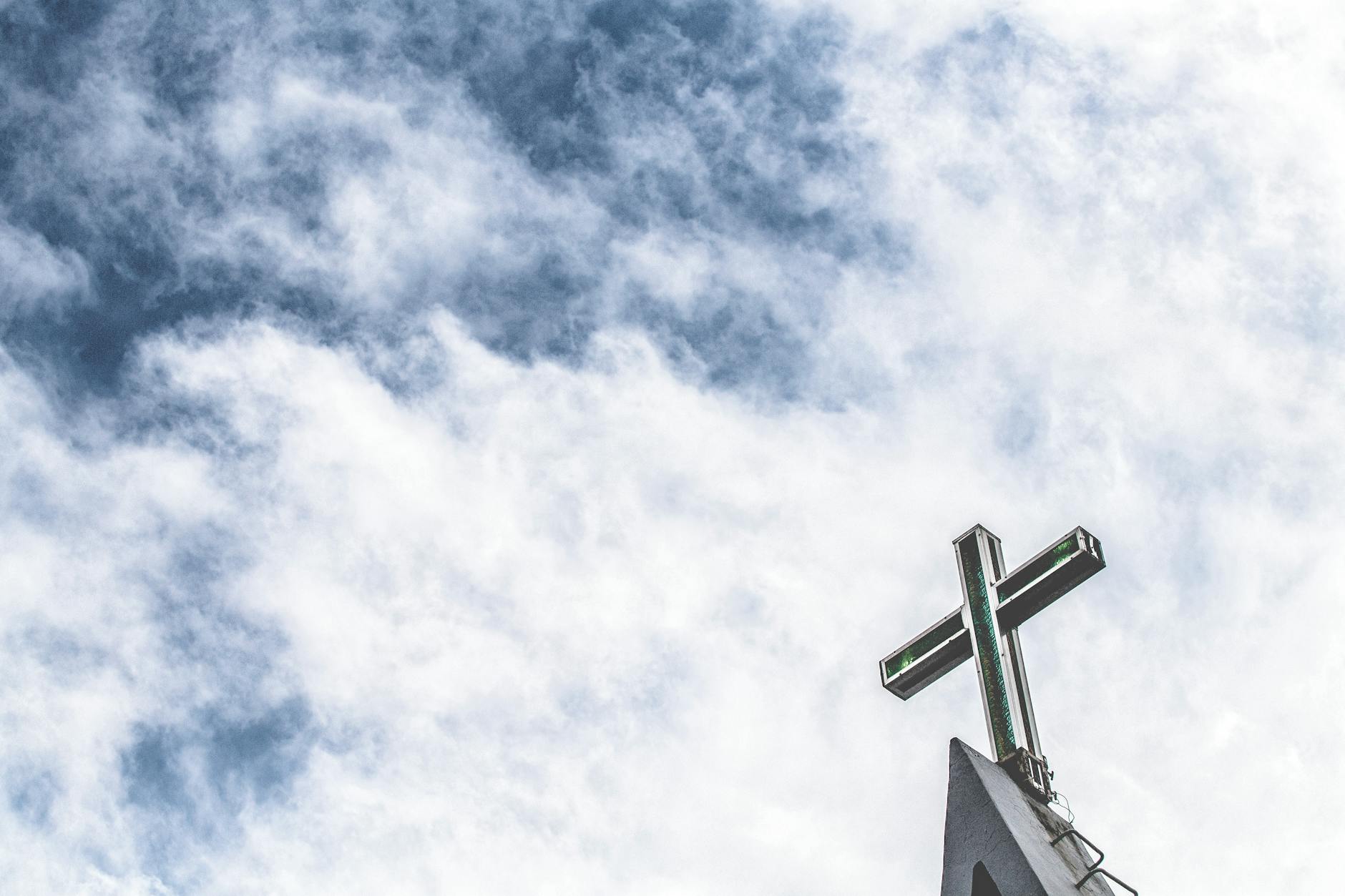 Capital Femme new believers page. Photo of a cross on top of some structure mainly with the sky as the backdrop.