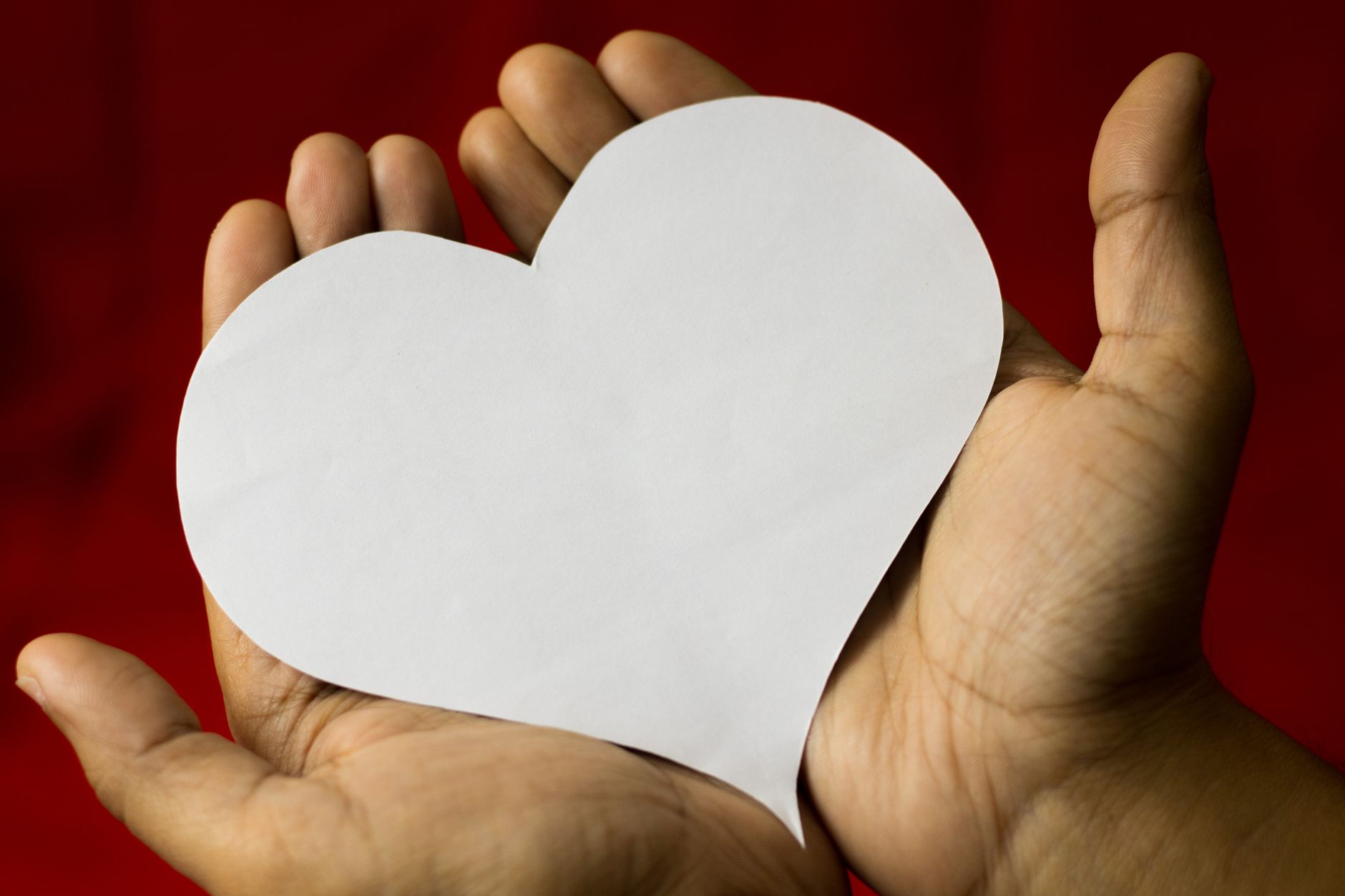 Capital Femme white cut out heart in hands. Give or support.